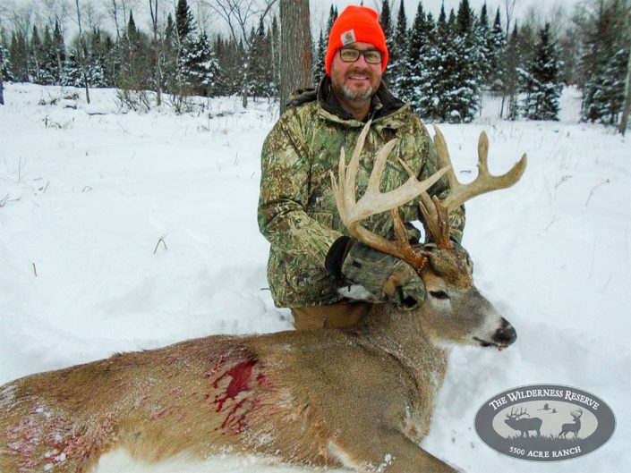 A man holds up his trophy buck 