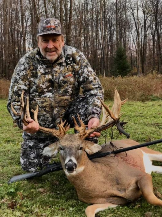 A man holds up the head of his trophy whitetail deer kill 