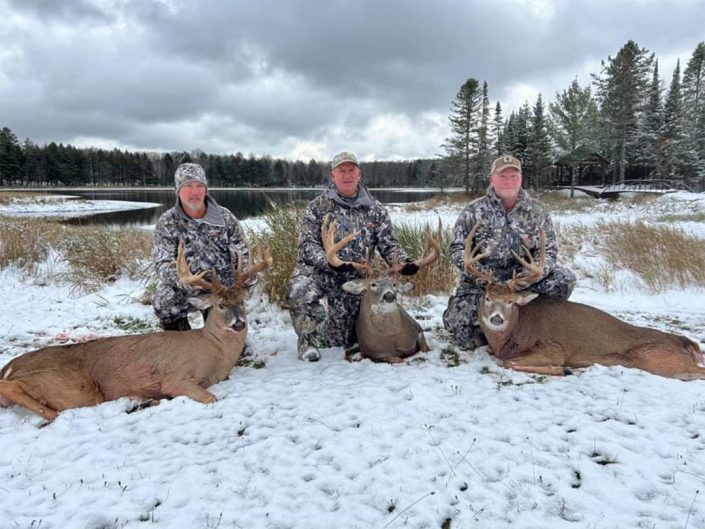 three hunters with three whitetail bucks
