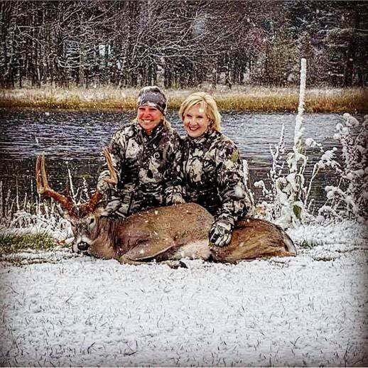 two women in the snow with deer kill