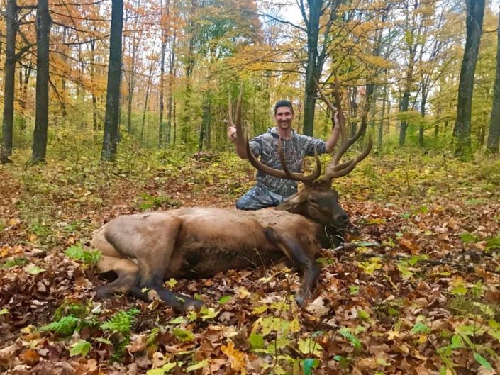 troy posing with trophy bull elk in fall folliage