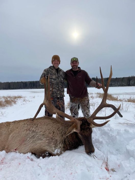 two men posing with Bull in snow